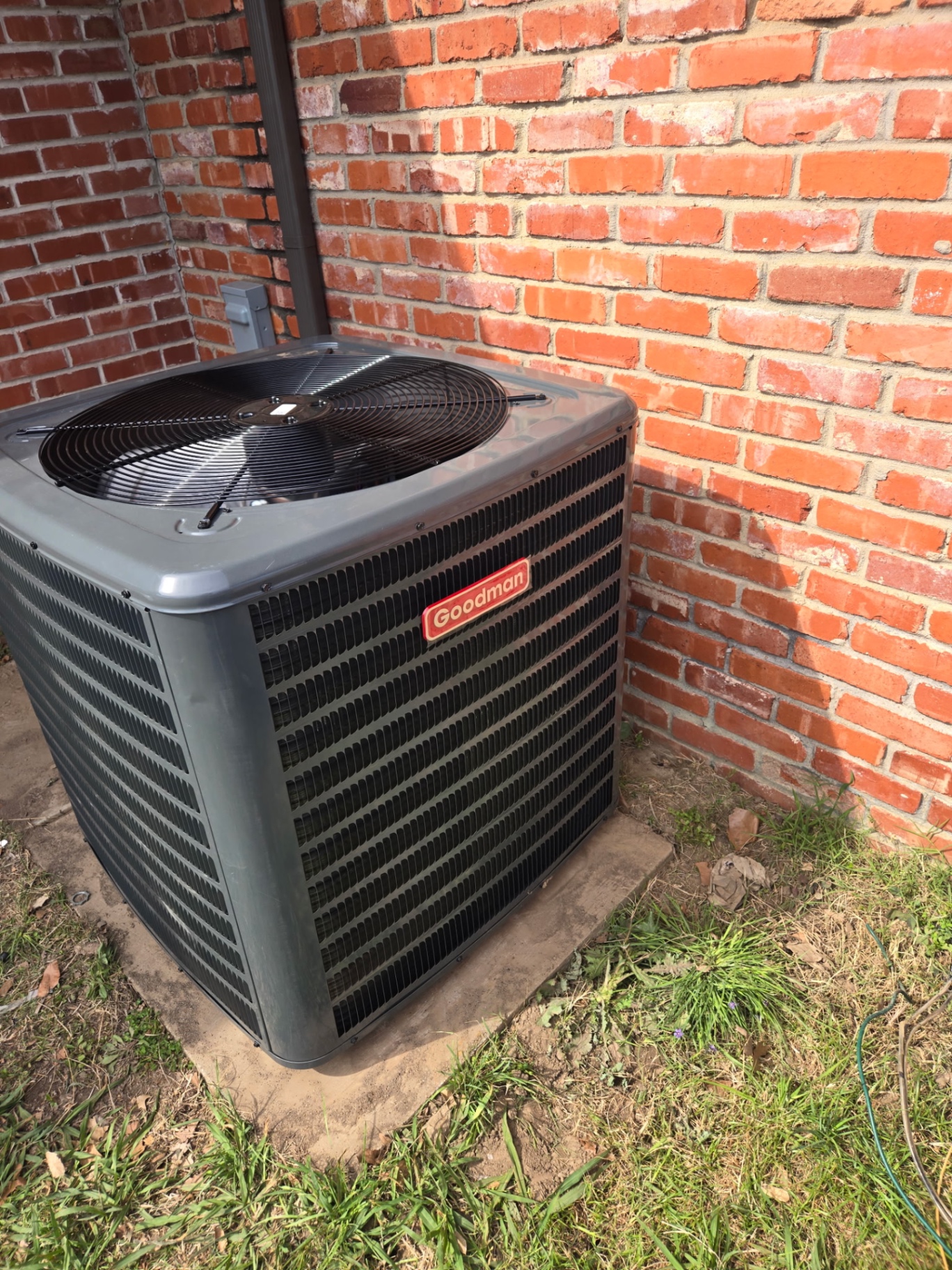 Goodman residential AC condenser install at brick home